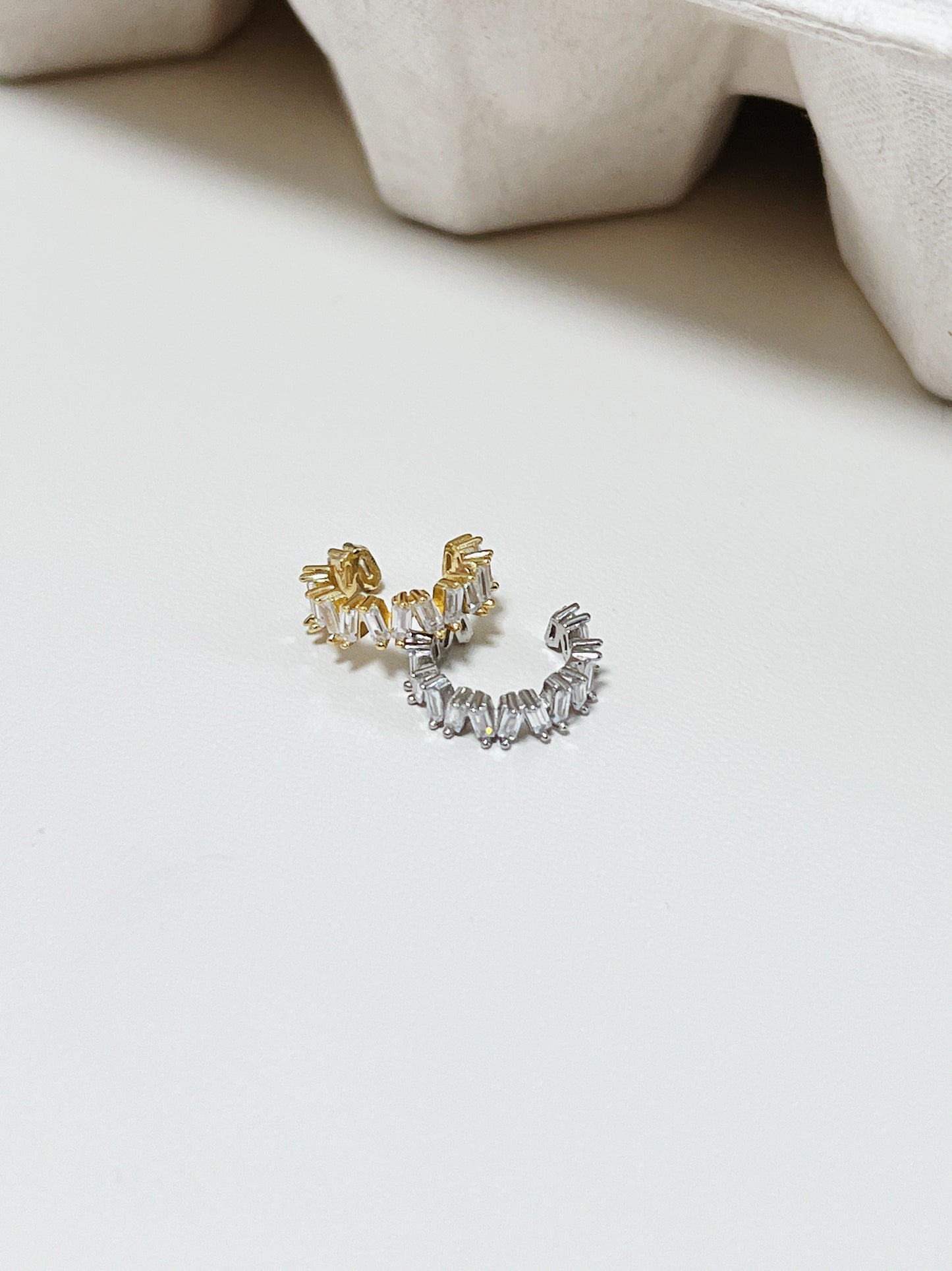 Pair of gold and silver cuff earrings on a light background