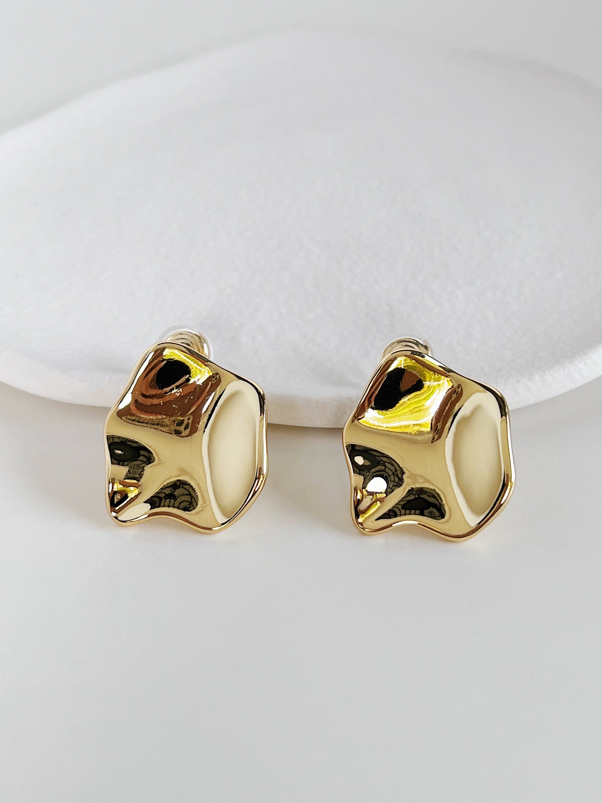 Gold clip earrings on a white background