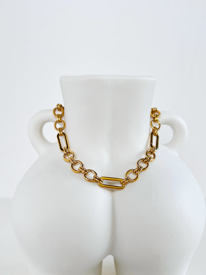 Gold chain bracelet on a white mannequin bust against a white background