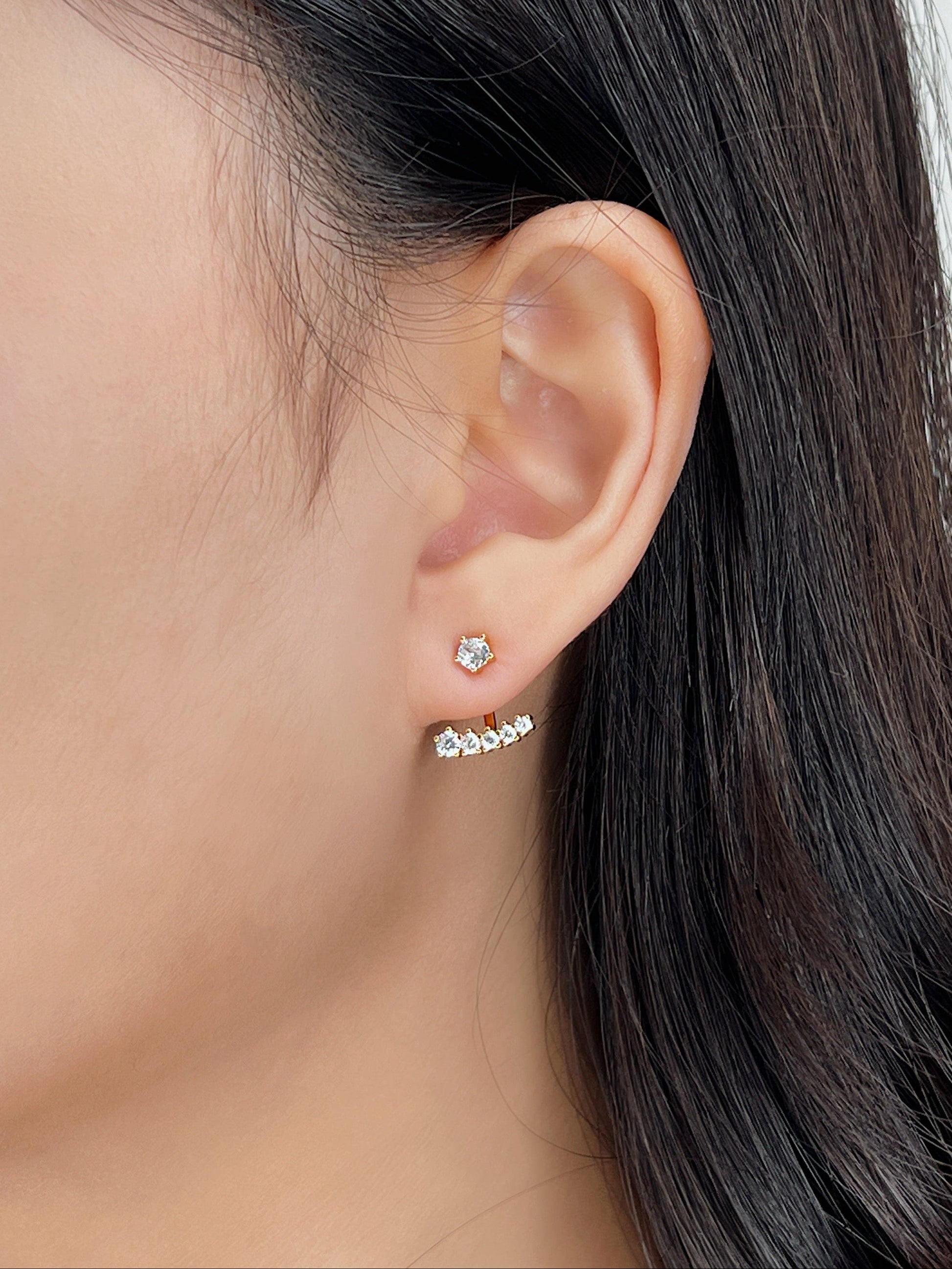 Close-up of an ear wearing diamond stud earrings with a blurred background