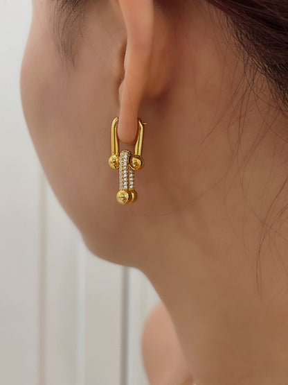 Fashionable gold interlocking earrings encrusted with pave diamonds, modeled on the side profile of an ear.