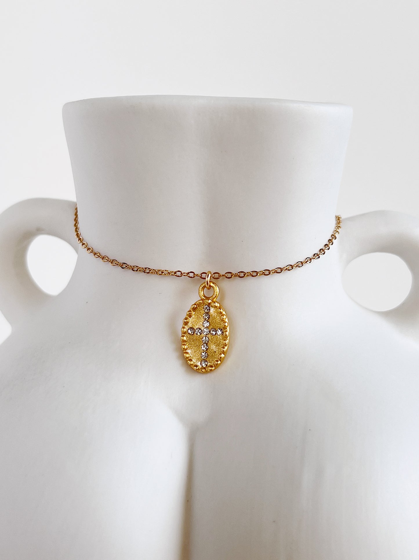 Close-up view highlighting the 5A cubic zirconia cross pendant of the Gianna necklace resting against the sculpted white ceramic body vase
