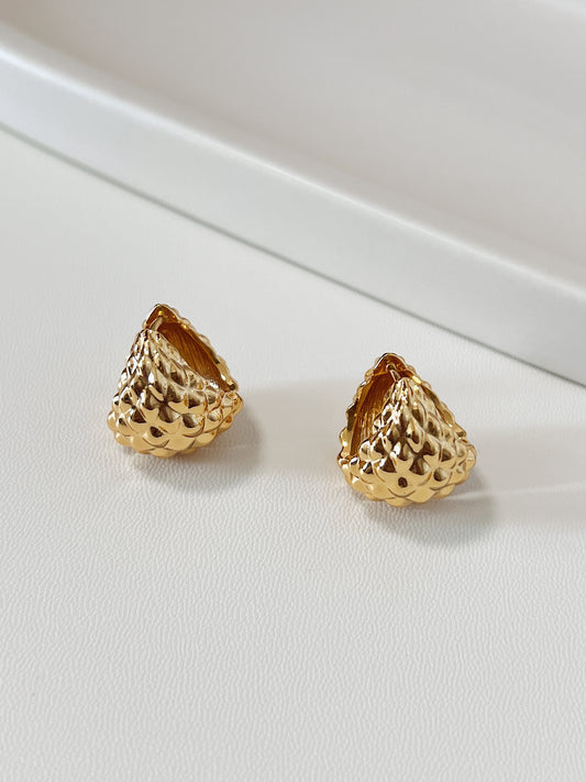 Gold textured hoop earrings on a white surface