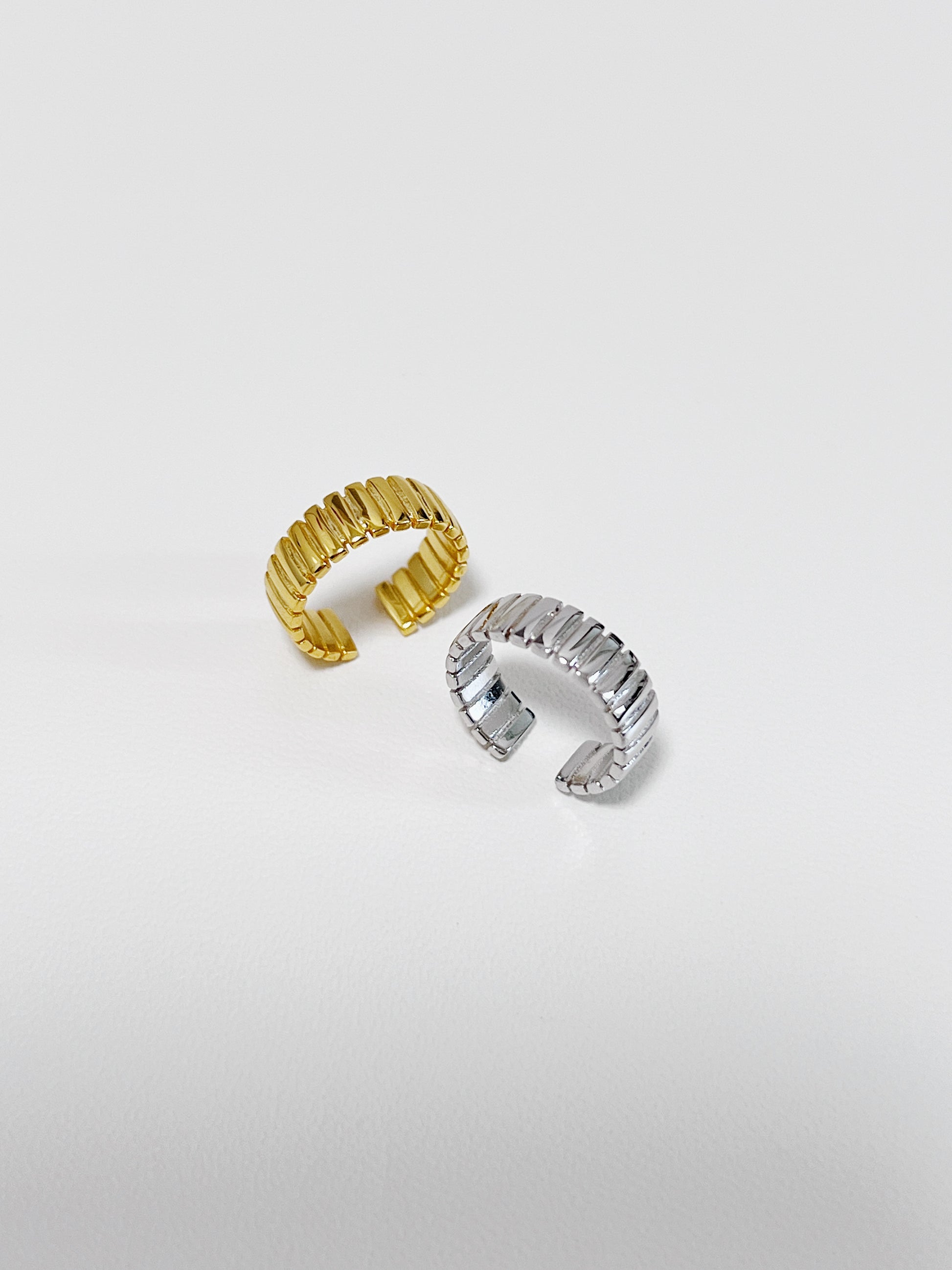 Gold and silver ribbed ear cuff on a light gray background