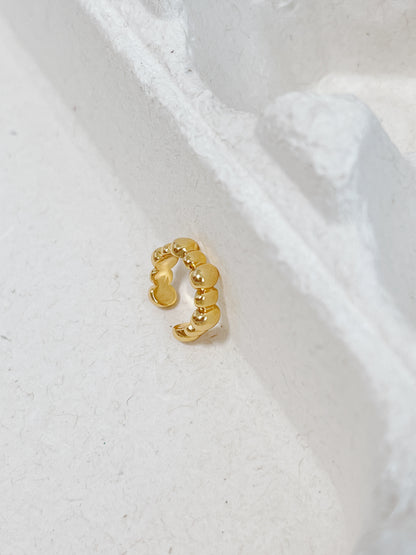Gold cuff earring on a white textured background