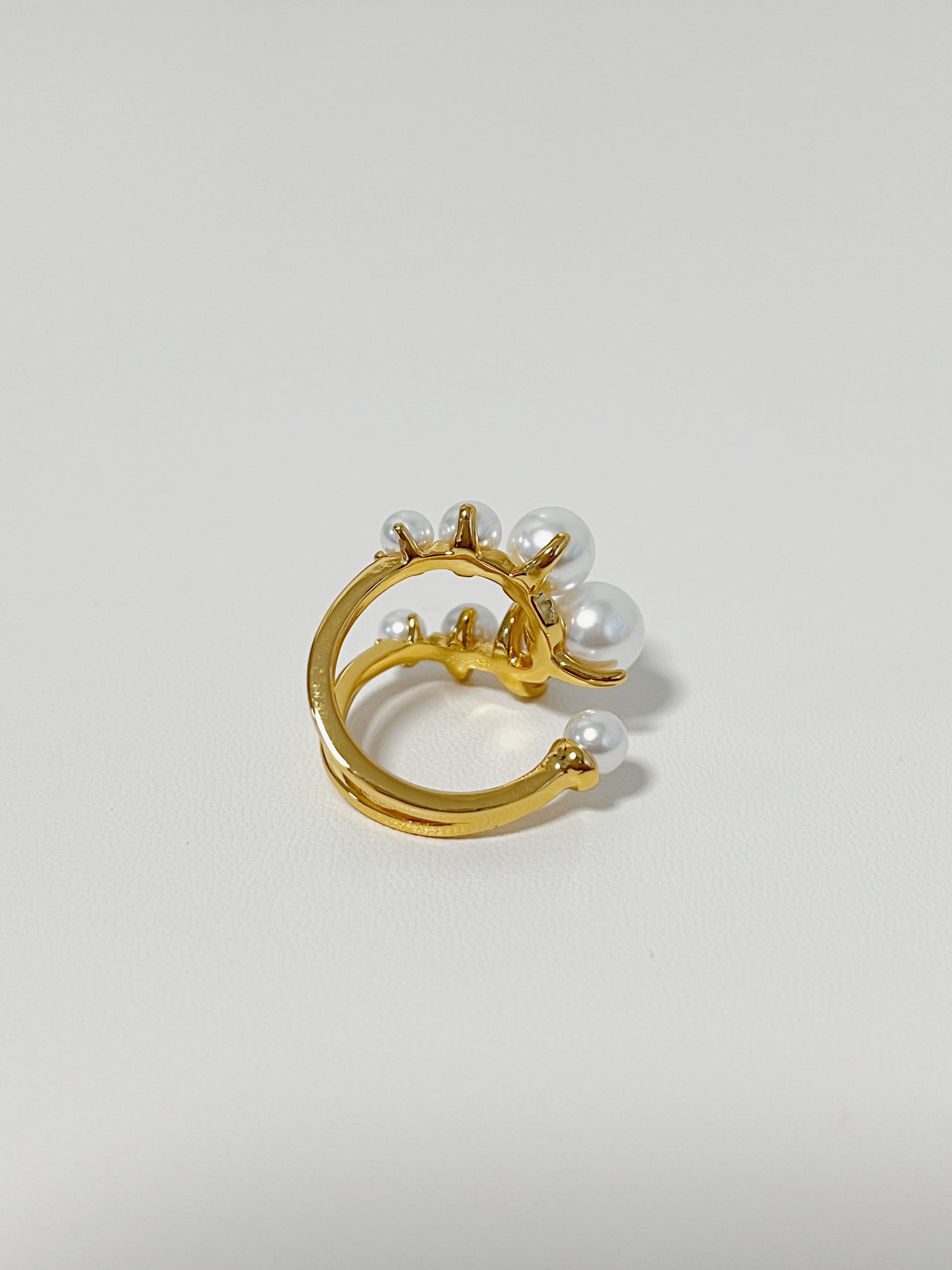 Gold ring with pearls on a light gray background