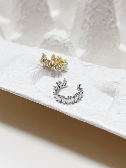 Gold and silver cz ear cuff earrings on a textured white surface