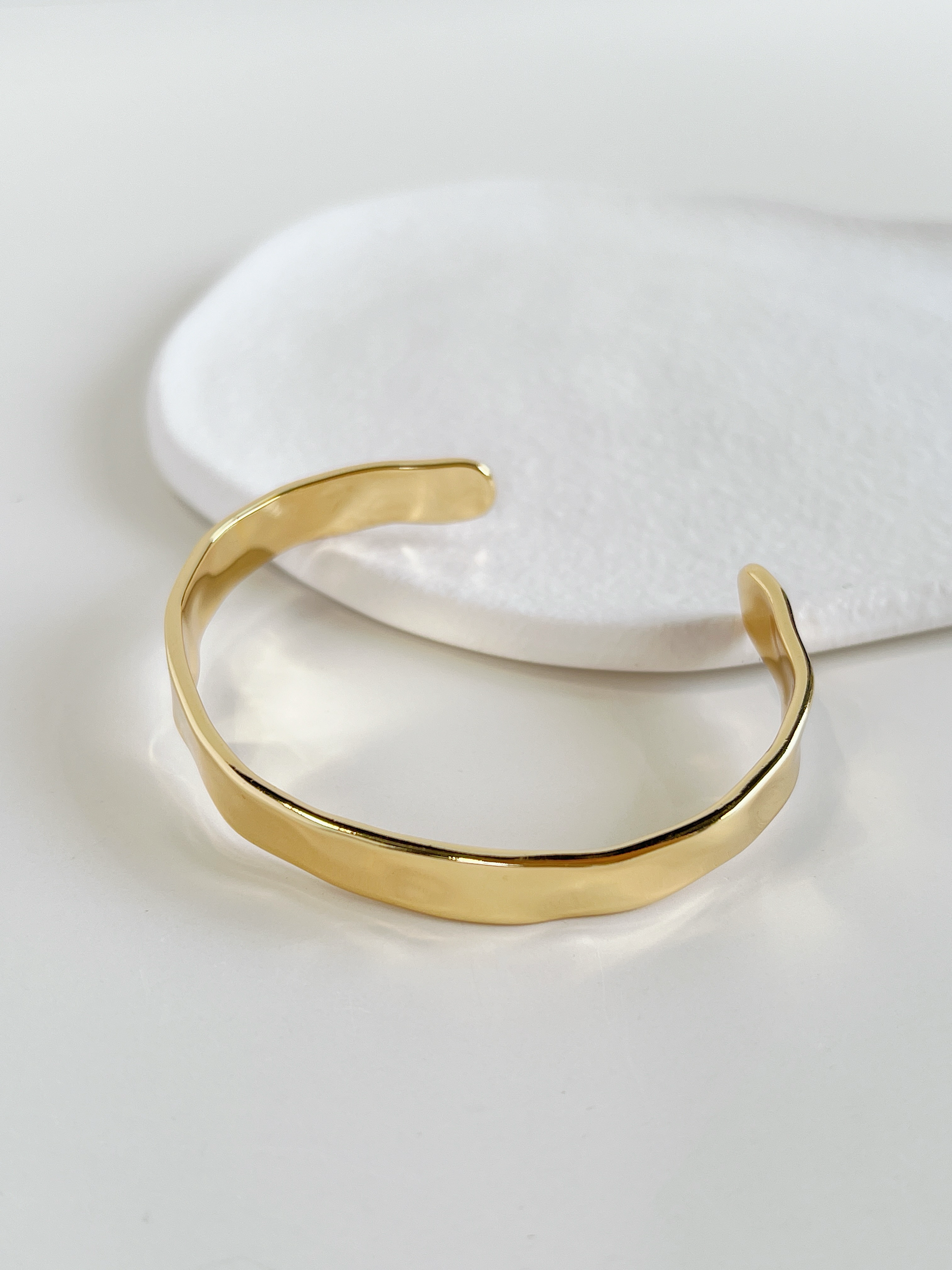 Sleek and modern gold-tone cuff bangle, a stylish minimalist jewelry piece.