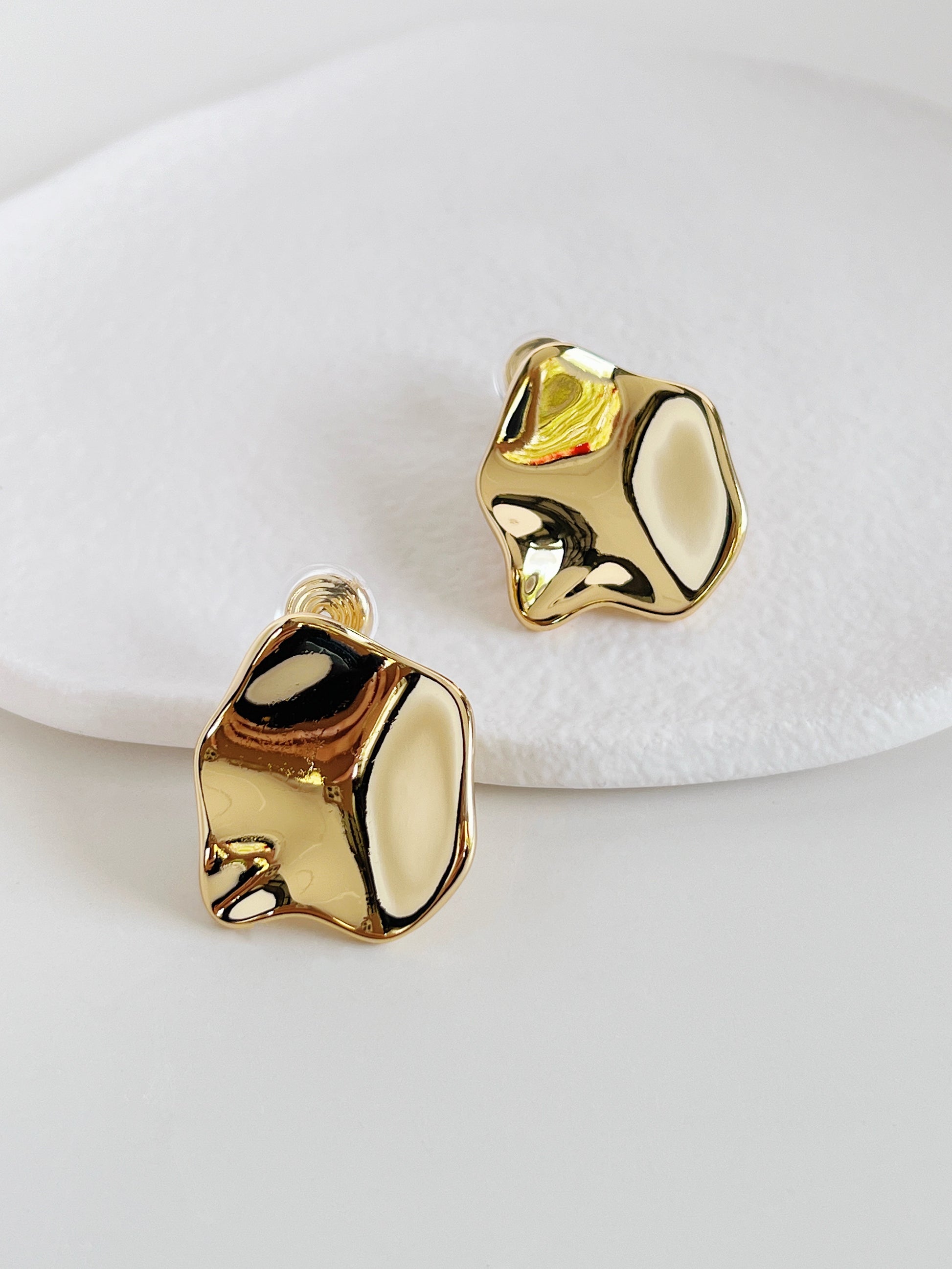Gold bold clip on earrings on a white background