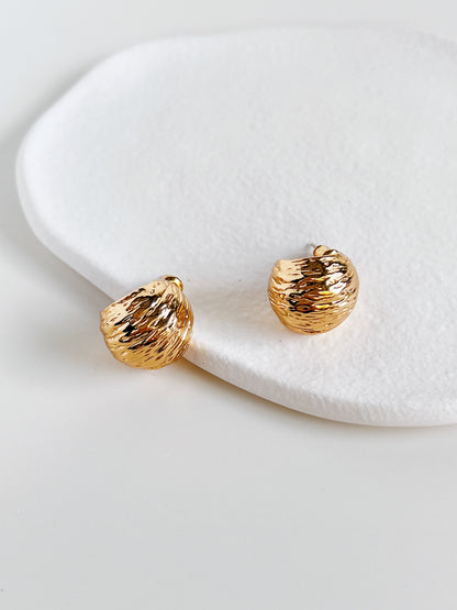 Gold earrings on a white ceramic surface