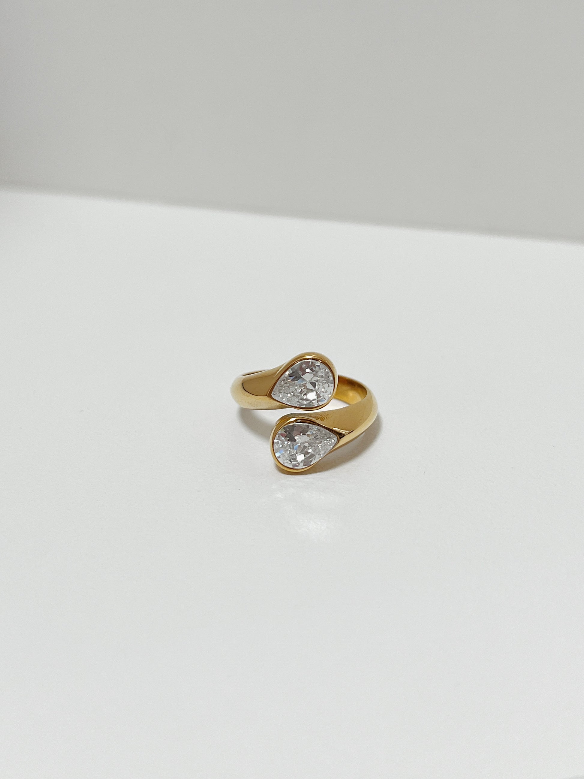 Gold ring with two pear-shaped gemstones on a white background