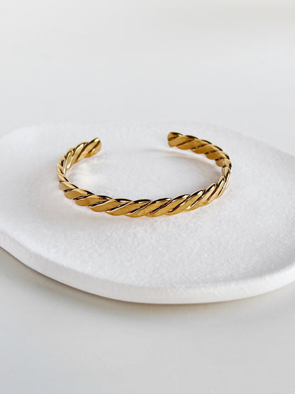 Gold braided bracelet on a white plate