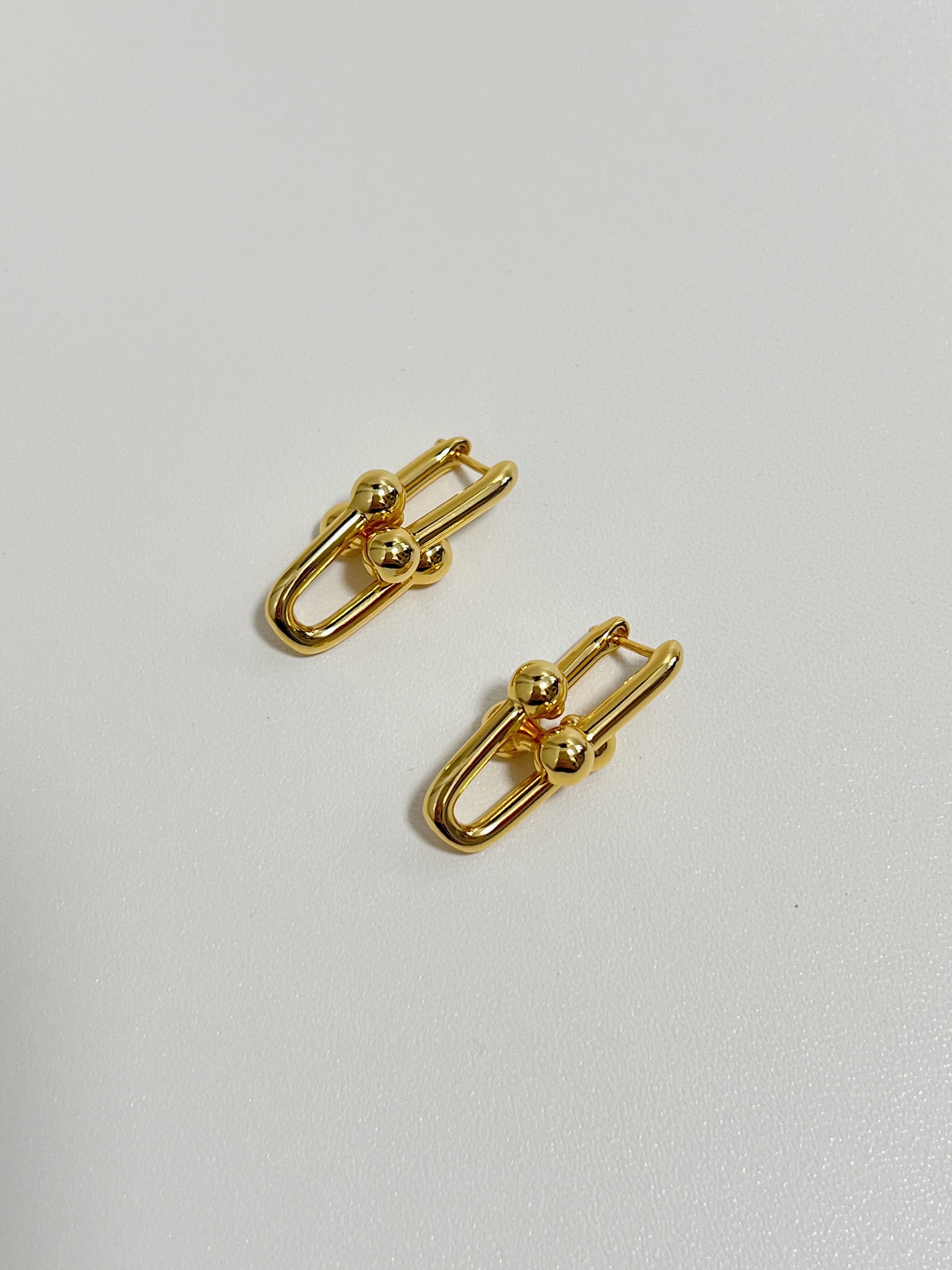 gold interlocking link earrings display on a white surface, perfect jewelry for special occasion.