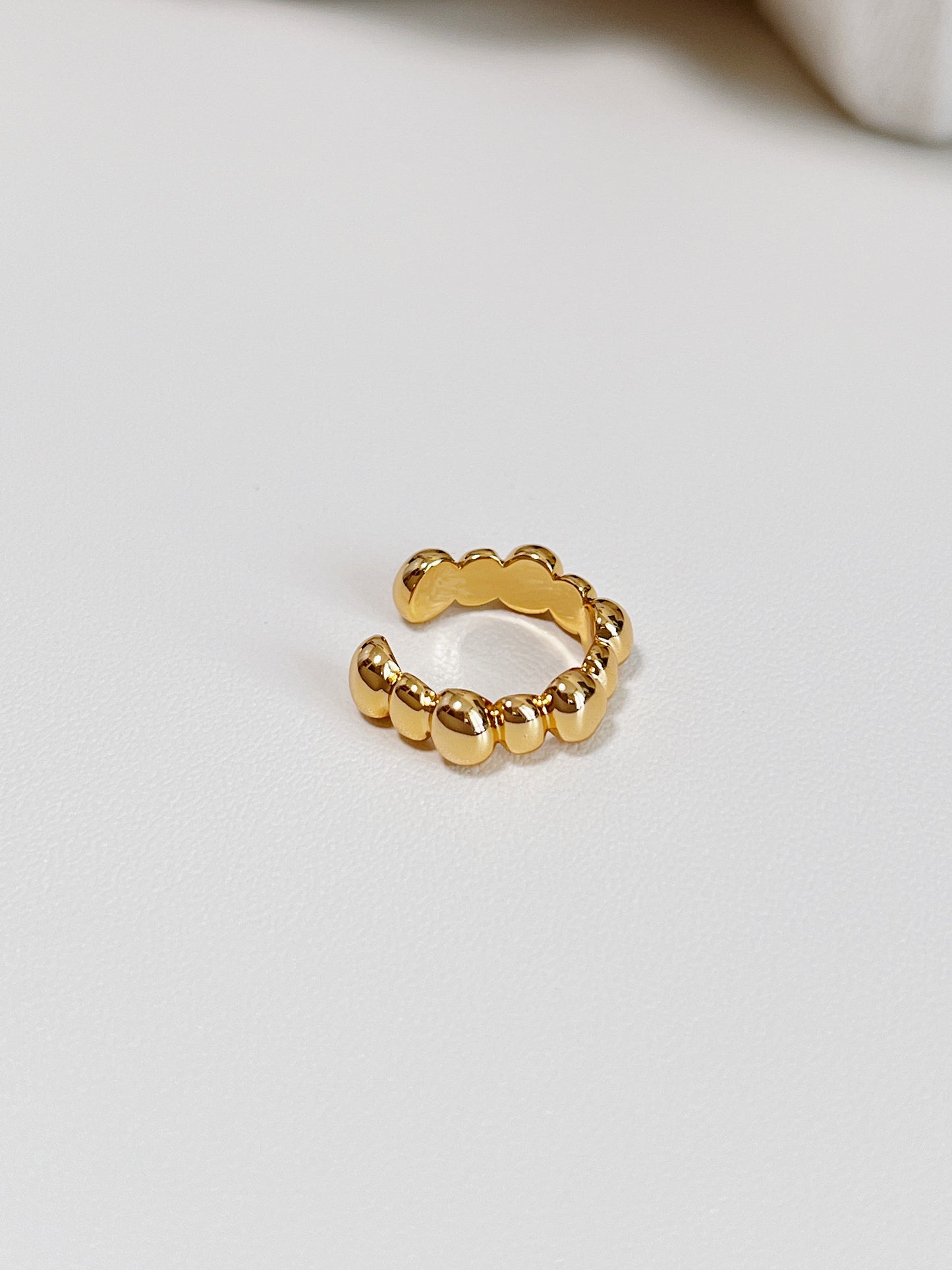 Gold beaded ear cuff on a light gray background