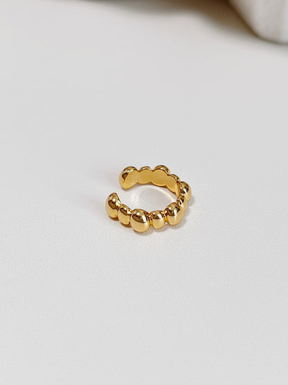 Gold beaded ear cuff on a light gray background