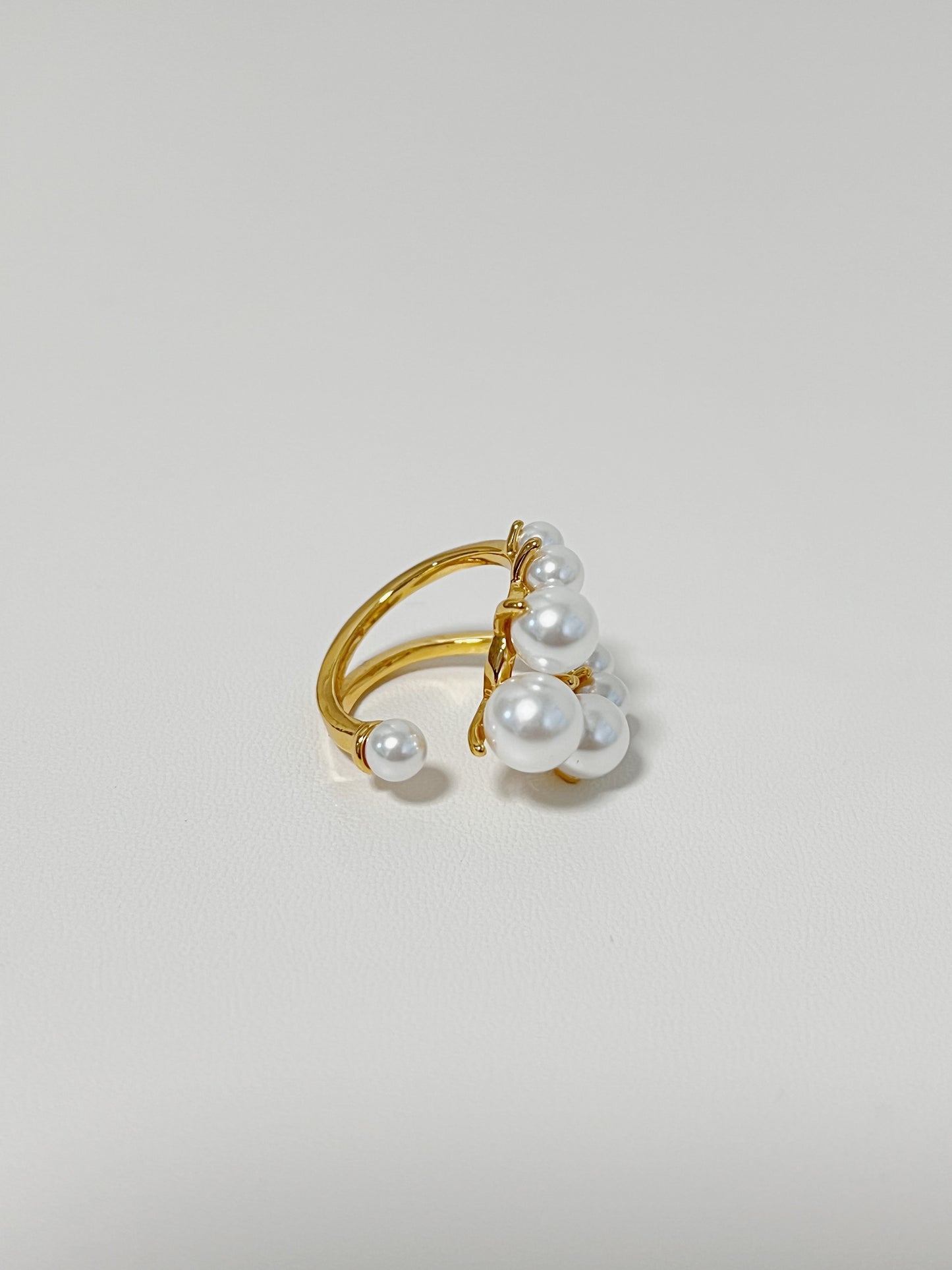 Gold ring with pearls on a light gray background