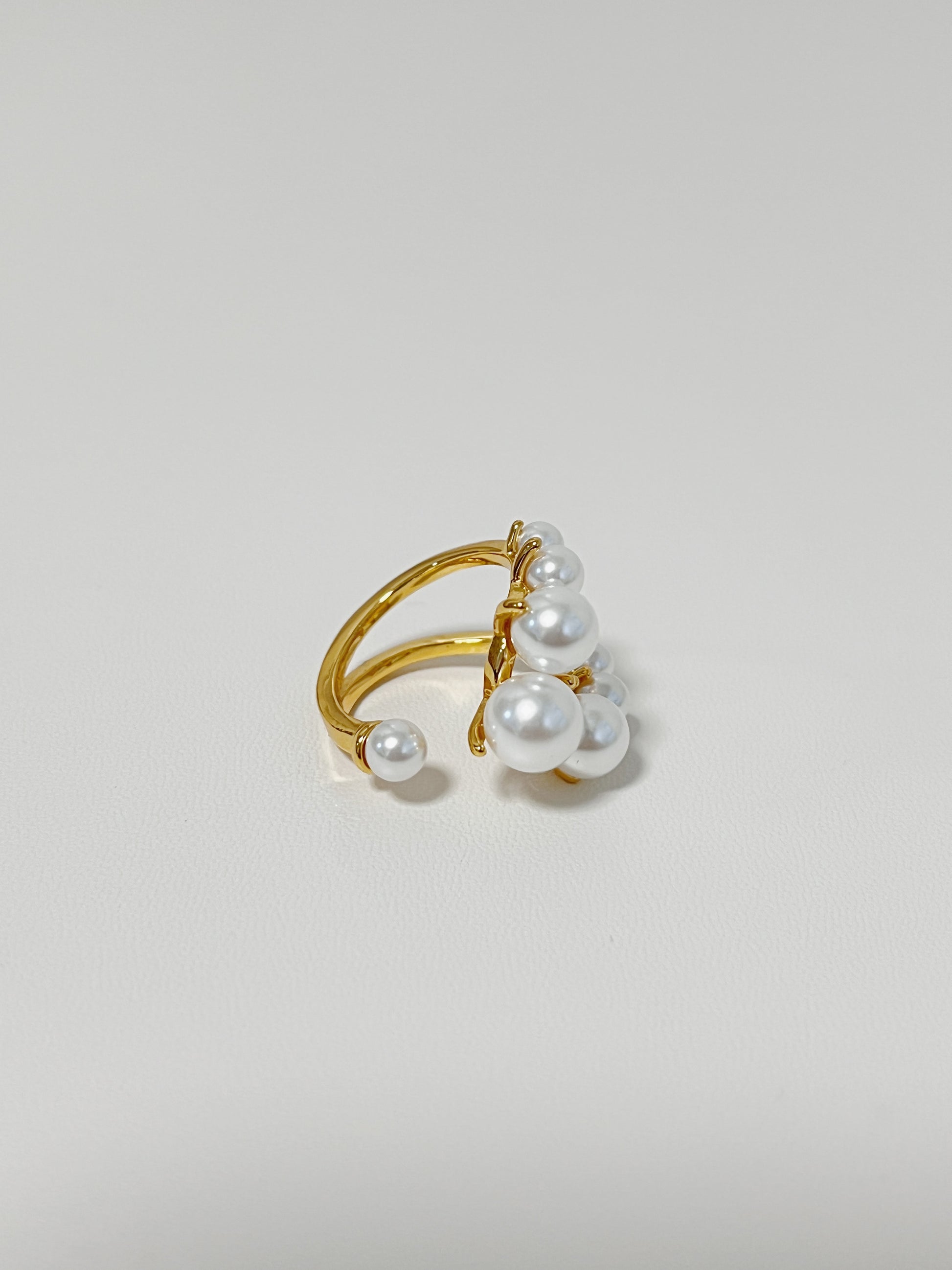 Gold ring with pearls on a light gray background