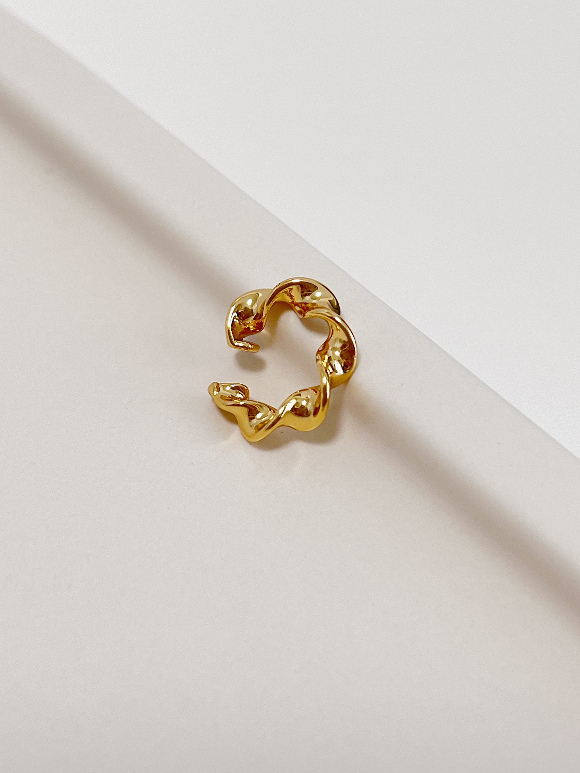 Gold spiral cuff earring on a light background