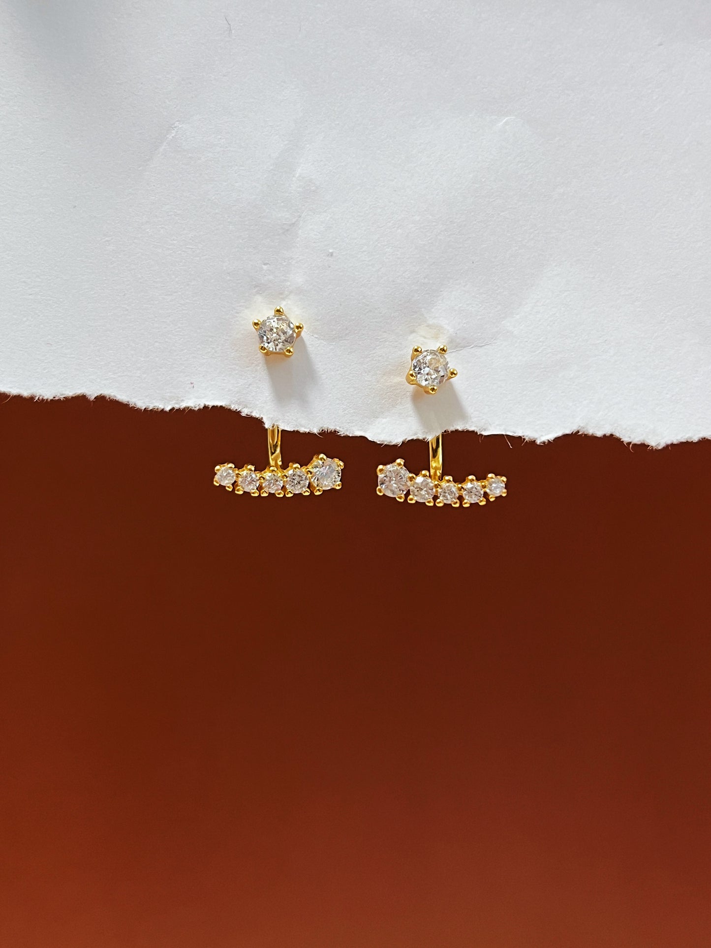 Gold diamond ear jacket earrings with gemstones on a white and brown background