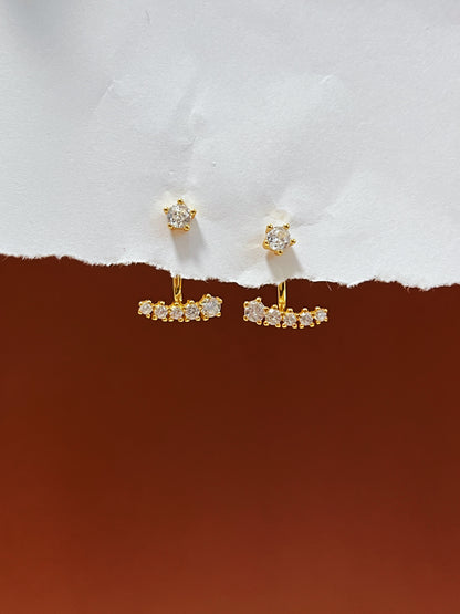 Gold diamond ear jacket earrings with gemstones on a white and brown background