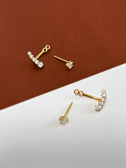 Set of gold earrings with clear stones on a brown and white background