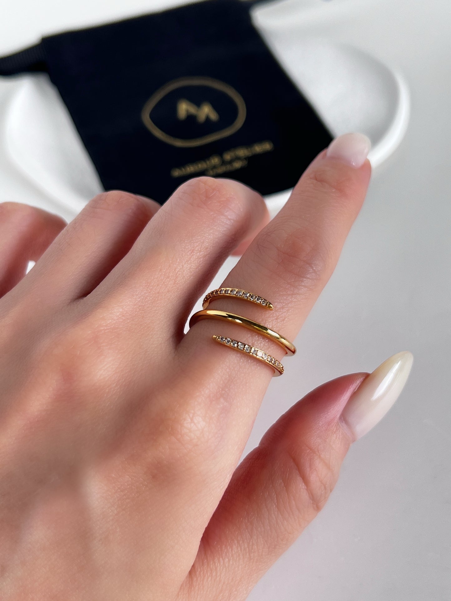Hand wearing a gold ring with a blurred background