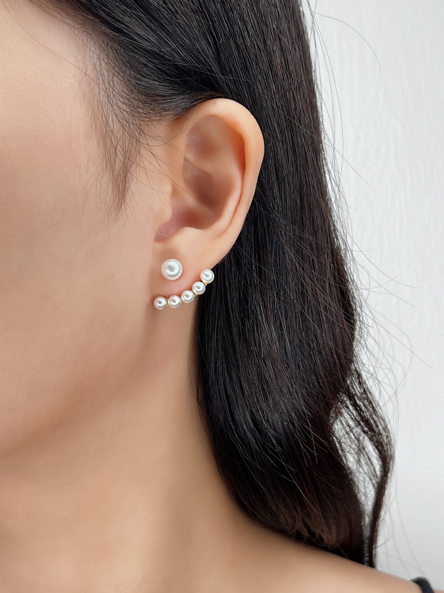Close-up of an ear wearing a pearl earring with a blurred background