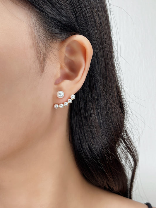 Close-up of an ear wearing a pearl earring with a blurred background