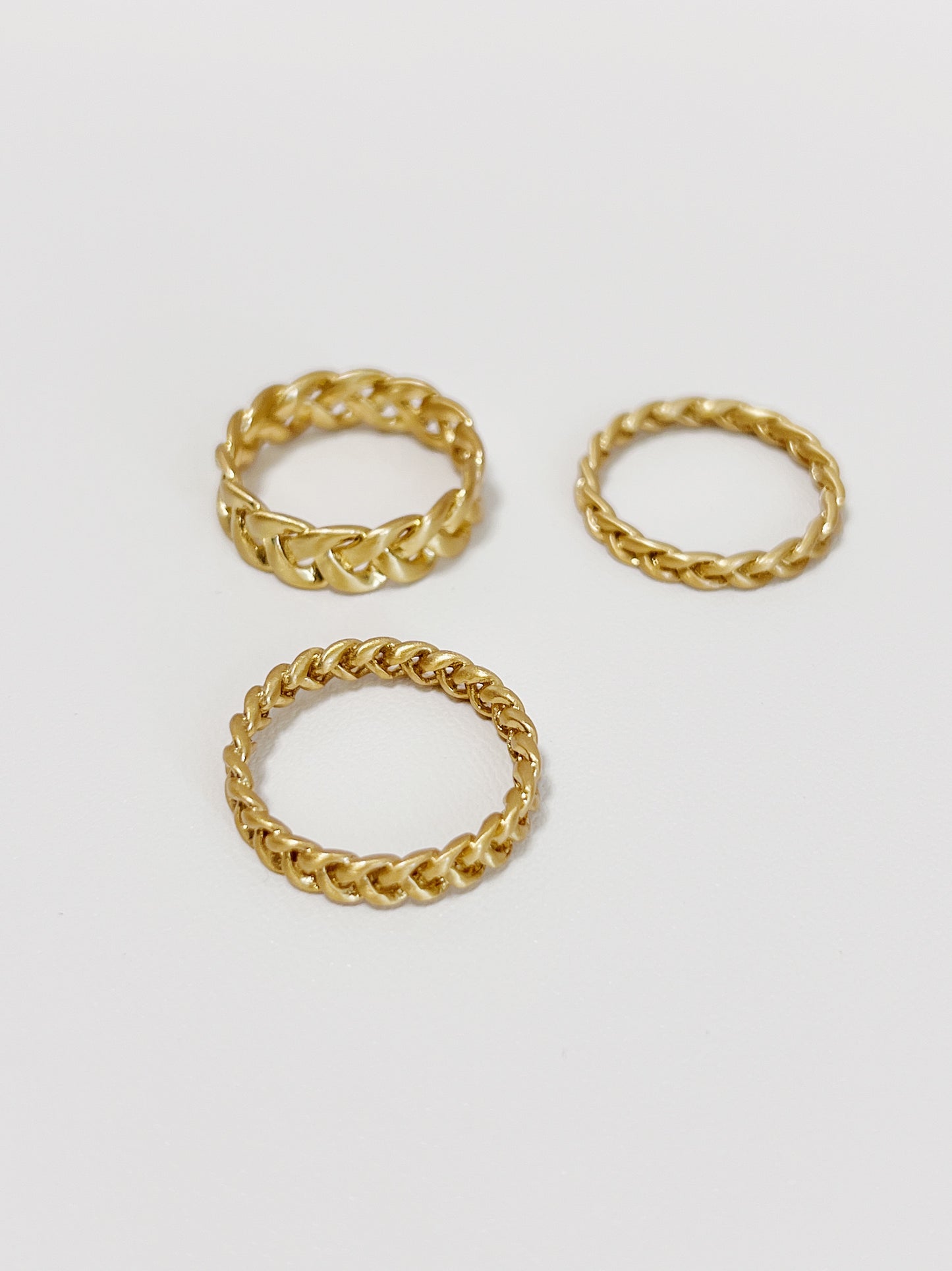 Three gold braided-style rings on a white background