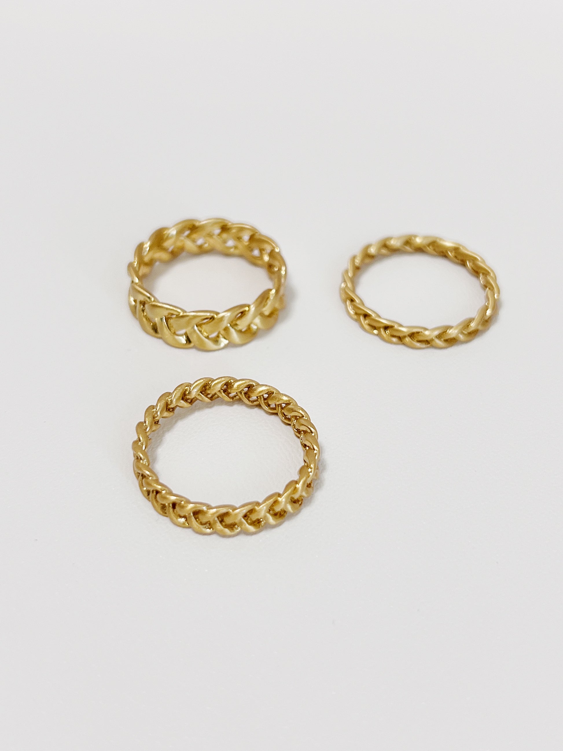 Three gold braided-style rings on a white background