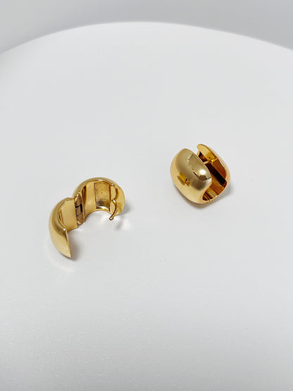 Gold wide hoop earrings on a white surface