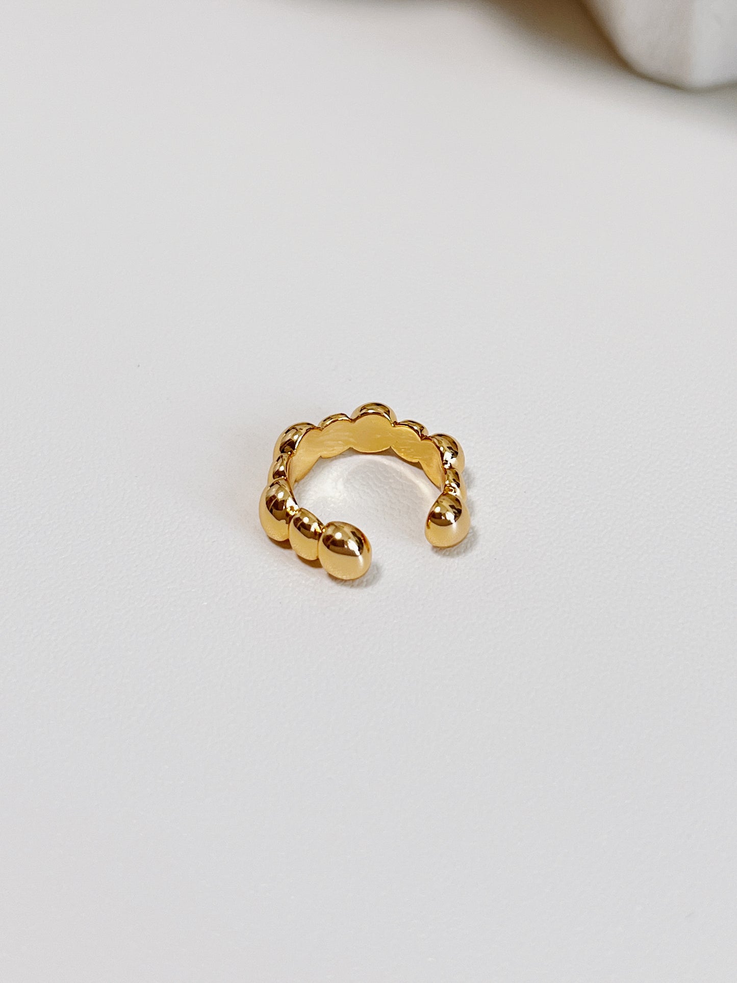 Gold ear cuff with a unique design on a light gray background