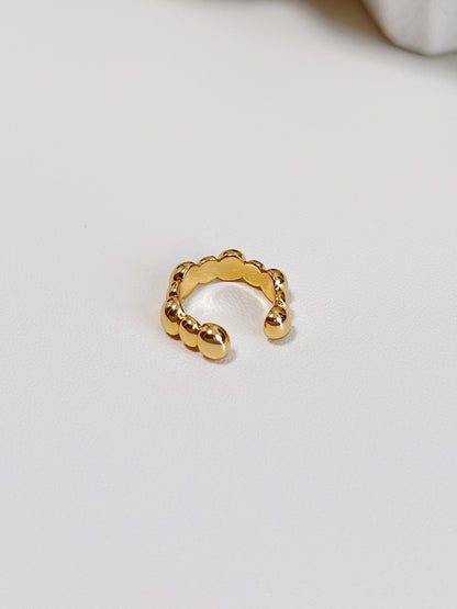 Gold ear cuff with a unique design on a light gray background