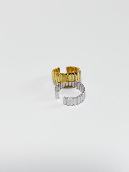 Two ear cuff, one gold and one silver, on a light gray background