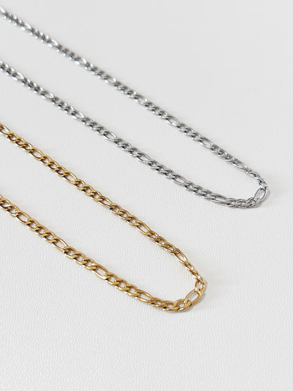 Two gold and silver figaro chain necklaces on a white background