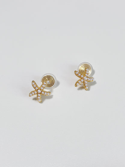 Gold starfish-shaped earrings on a light gray background