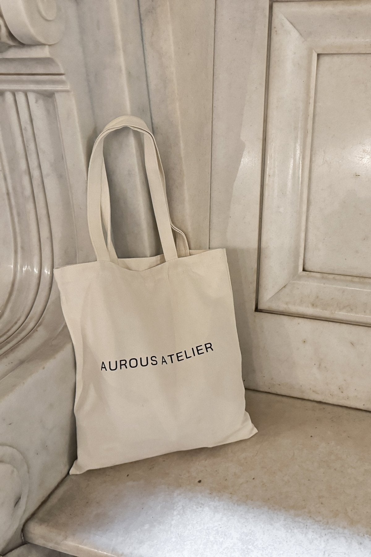 Aurous Atelier Canvas Tote Bag place on a marble seat