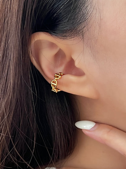 Close-up of a person wearing a gold chain ear cuff with a blurred background