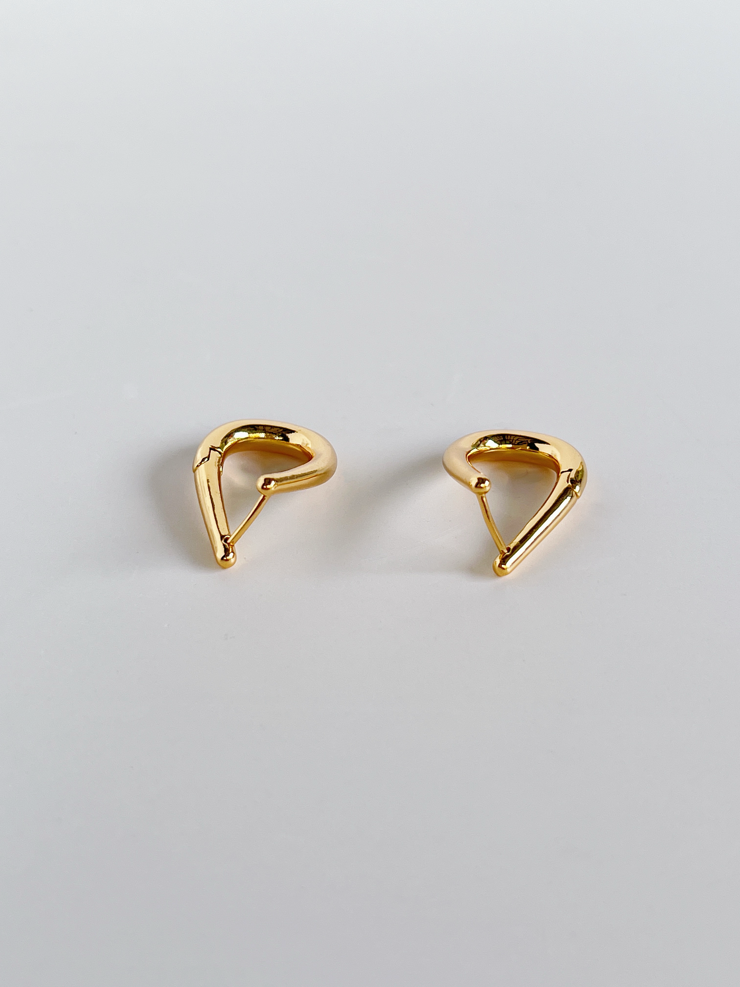 Pair of gold oblong-shaped earrings on a light gray background