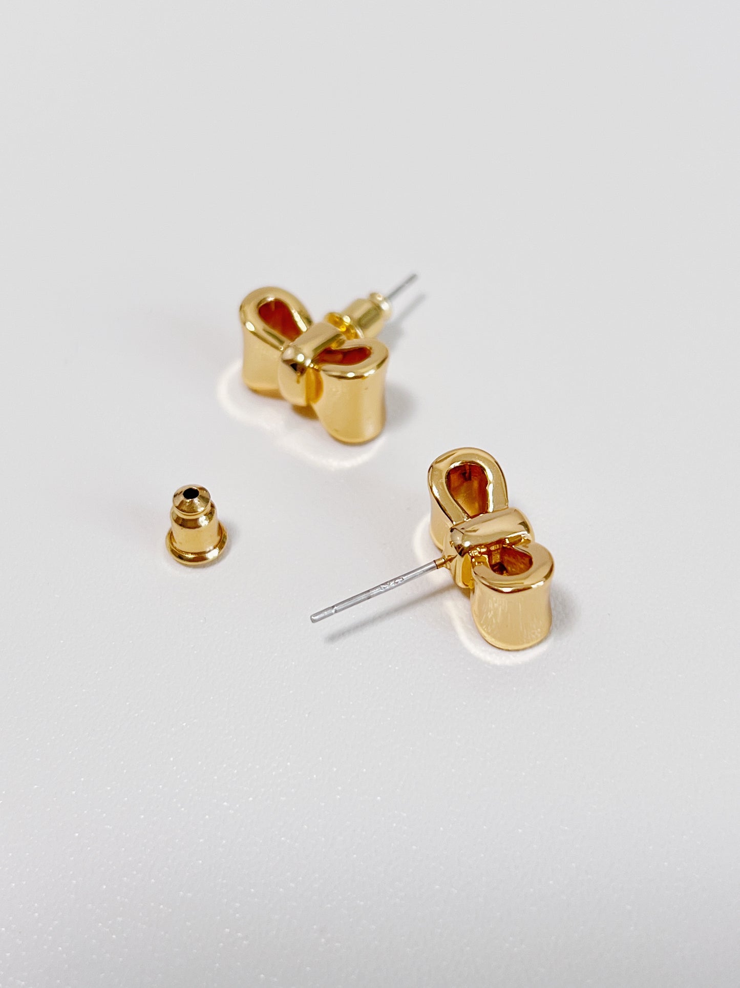 Gold bow-shaped earrings on a light gray background