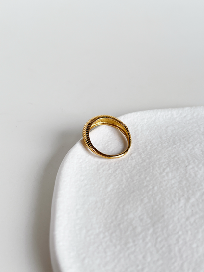 Gold dome ring on a white ceramic plate with a light gray background