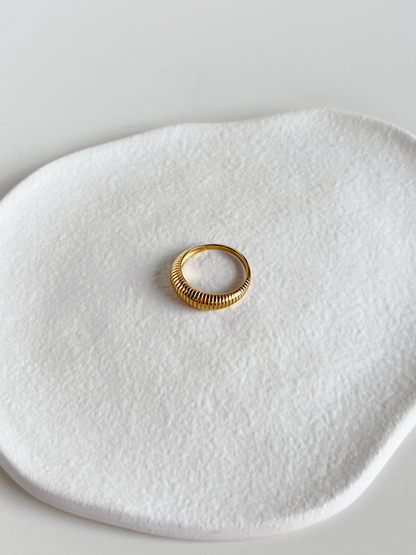 Gold ribbed dome ring on a textured white surface