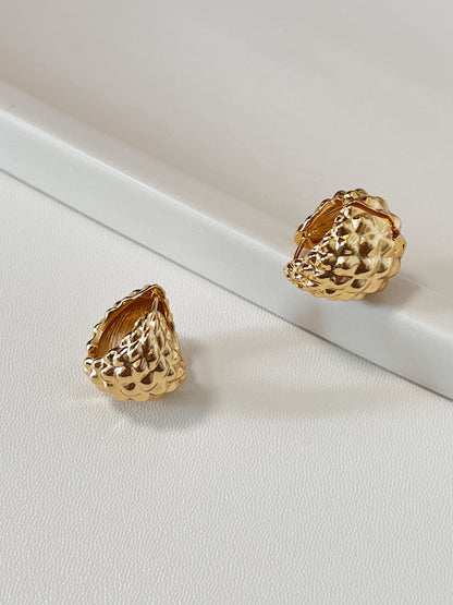 Gold hoop earrings on a white surface