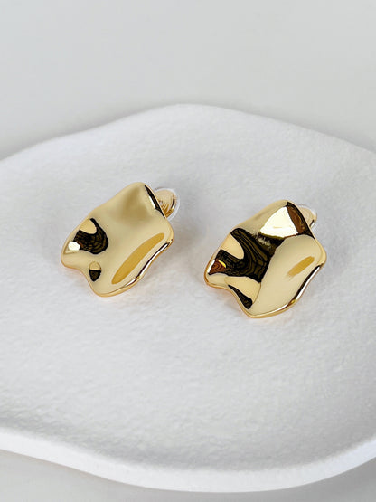 Gold clip on earrings on a white surface