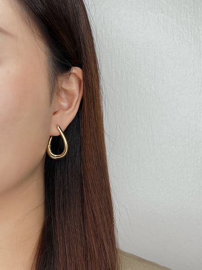 Minimalist Gold hoop earring worn by a person with long brown hair against a white background