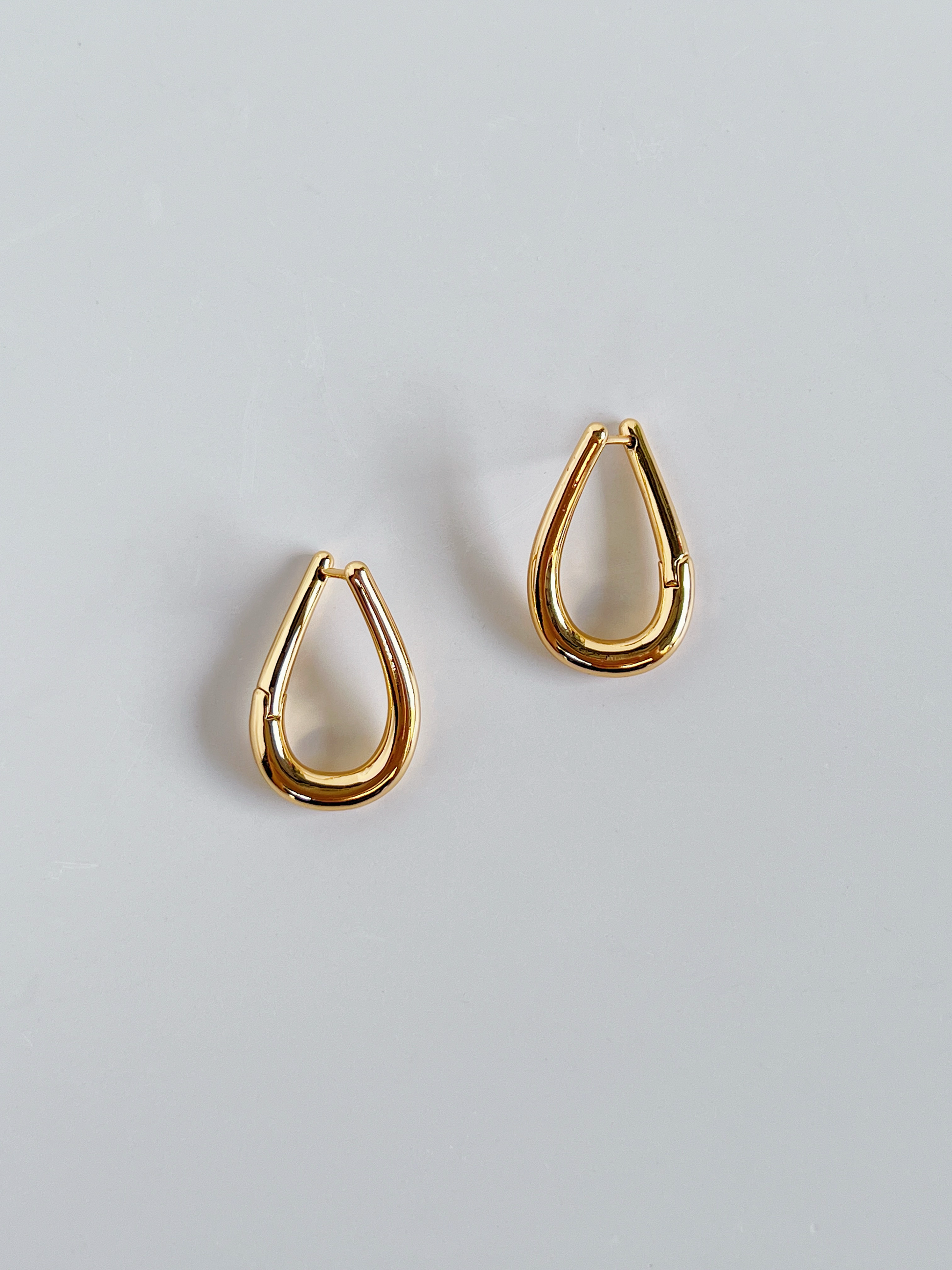 Pair of gold twist hoop earrings on a light gray background