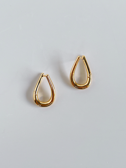 Pair of gold twist hoop earrings on a light gray background