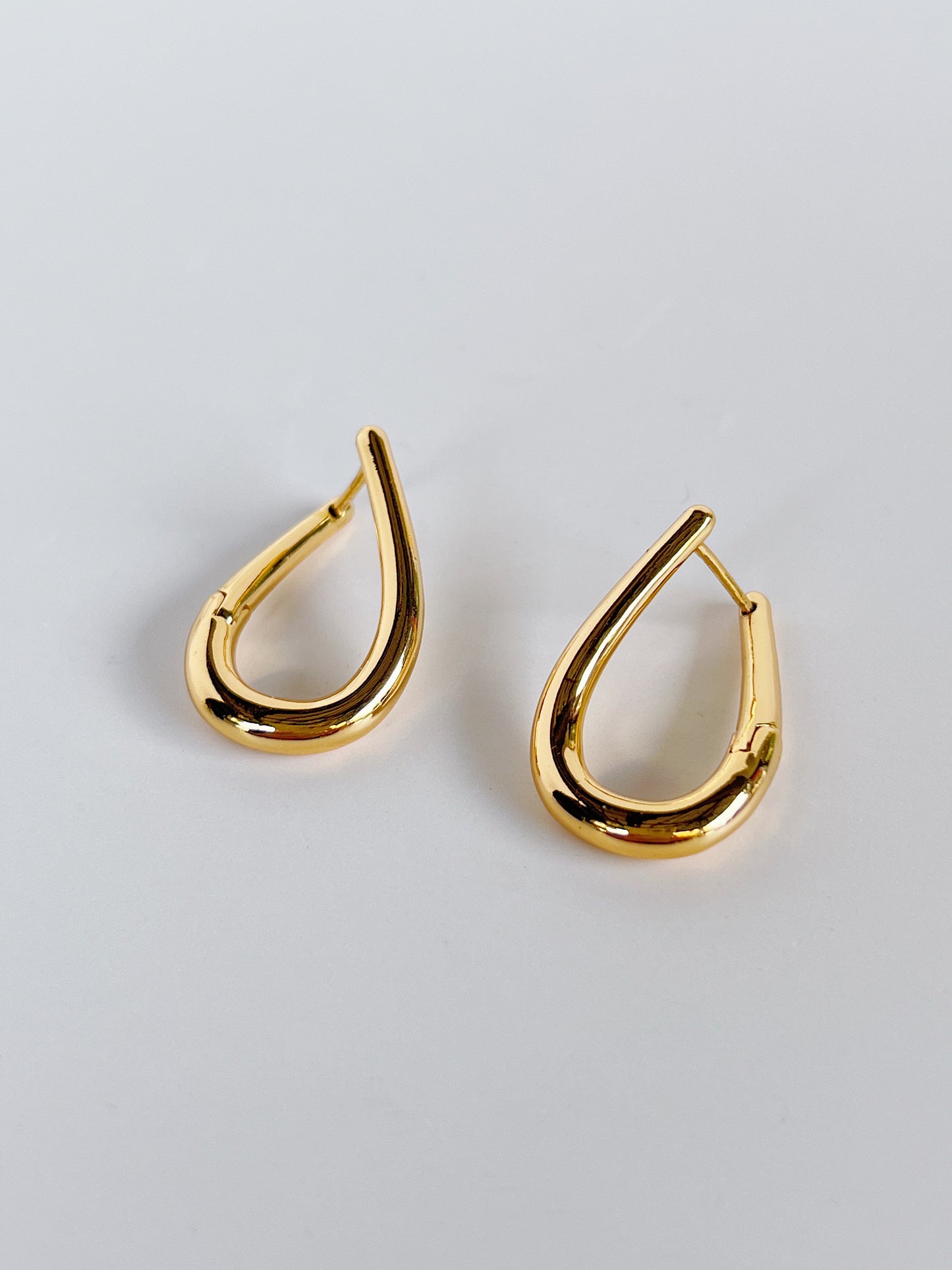 Gold twist hoop earrings on a light gray background