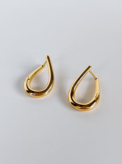 Gold twist hoop earrings on a light gray background