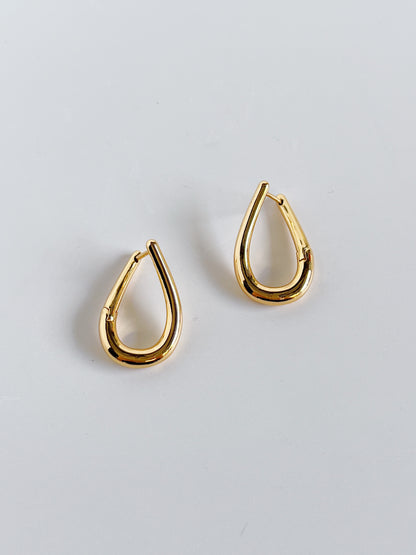 Gold twill hoop earrings on a light gray background